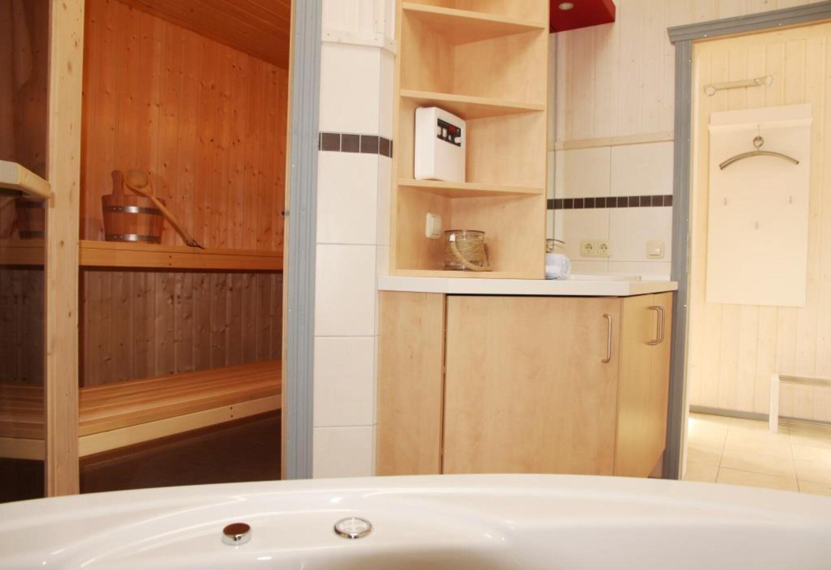 A bathroom with a wooden vanity, a white bathtub, and a shelf with toiletries.