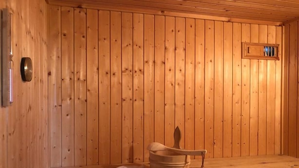 Un sauna en bois, avec un banc, un seau et des serviettes.