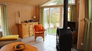 Une pièce avec une cheminée, un canapé, un fauteuil et un meuble en bois.
