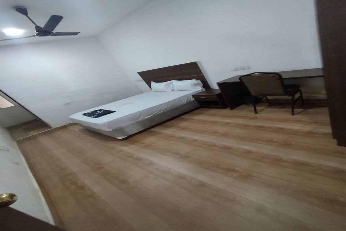 A bedroom with a bed, a desk, and a chair.
