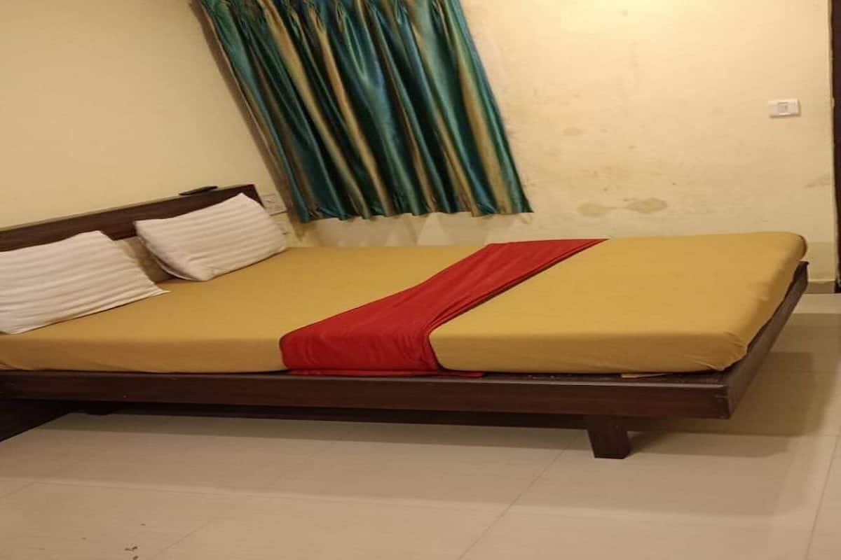 A bed with a yellow mattress, a red blanket, and white pillows.