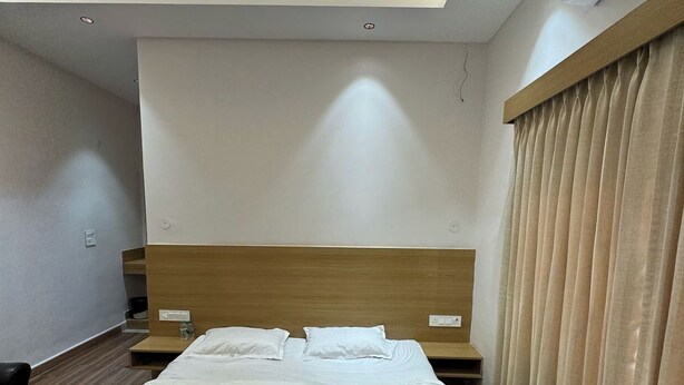A modern hotel room with a large bed, wooden headboard, and a ceiling fan. - Hotel Clay Inn (Sohna)