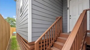 Un edificio residencial con una escalera de madera que conduce a una puerta principal.