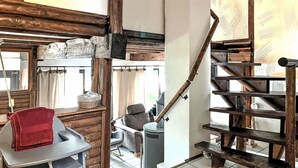 A rustic interior with exposed wooden beams, a staircase, a seating area with a red towel, and a window with curtains. - Tim´s Alm am Silbersee by Interhome (Frielendorf)