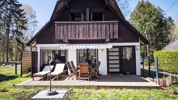 A wooden chalet with a balcony, a patio with outdoor furniture, and a view of the surrounding forest. - Tim´s Alm am Silbersee by Interhome (Frielendorf)