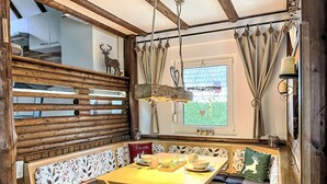 A rustic dining area with a wooden bench, a table with plates and cups, and a window with curtains. - Tim´s Alm am Silbersee by Interhome (Frielendorf)
