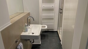 A narrow bathroom with a white sink, a mirror above it, and a towel rack with a towel. - Pempelforter Domicile (Düsseldorf)