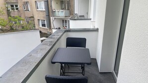 A balcony with a table and two chairs, a white wall, and a view of neighboring buildings. - Pempelforter Domicile (Düsseldorf)