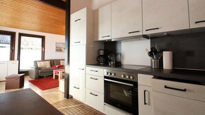 A modern kitchen with white cabinets, a stainless steel stove, and a red rug. - Freistehender Ferienbungalow im Fachwerkstil (Butjadingen)
