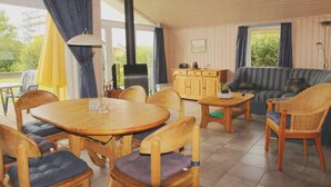 Una habitación acogedora con una mesa y sillas de madera, un sofá y un armario.