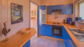 A compact kitchen with blue cabinets, a stove, and a sink. - Ferienhaus mit Sauna im Ferienpark Mirow (Mirow)