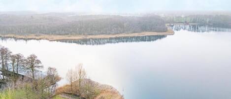A calm lake with a dock and a small building on the shore.
