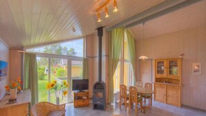 A spacious living area with a fireplace, dining table, and comfortable seating. - Ferienhaus mit Sauna im Ferienpark Mirow (Mirow)
