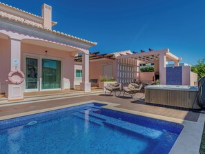 A swimming pool with a hot tub and outdoor seating area.