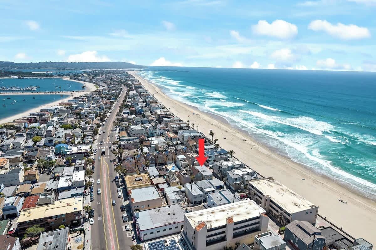 Un paysage urbain côtier avec une longue plage, une route principale et des bâtiments le long du littoral.