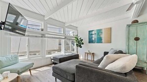 A spacious living area with a grey sofa, a teal armchair, and a teal cabinet. - Mission Beach w/ OceanViews Surfboards Parking AC (San Diego)