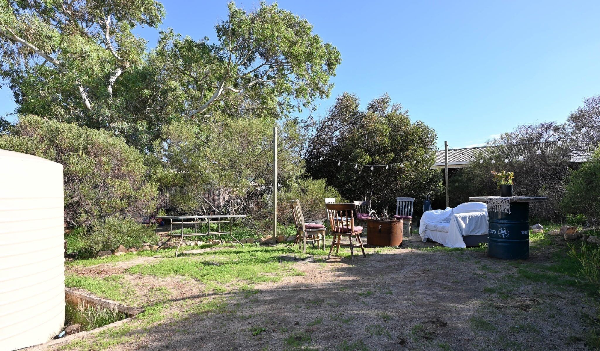 A backyard with a covered outdoor seating area, a metal fence, and trees.