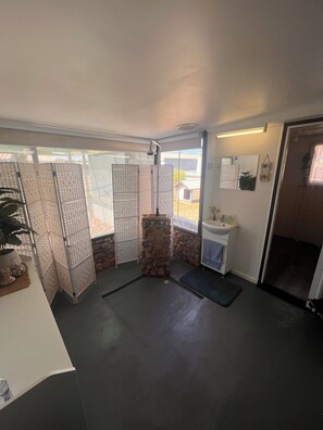 Een badkamer met een accentmuur van steen, een wastafel, een spiegel en een douchegedeelte.