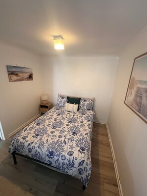 A bedroom with a bed, a nightstand, a lamp, and a painting on the wall. - Beachfront Bliss with Stunning Eyre Peninsula Views (Miranda)
