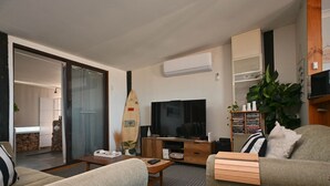Ein Wohnzimmer mit Fernseher, Holzmöbeln, einem Surfbrett und einem Bücherregal.