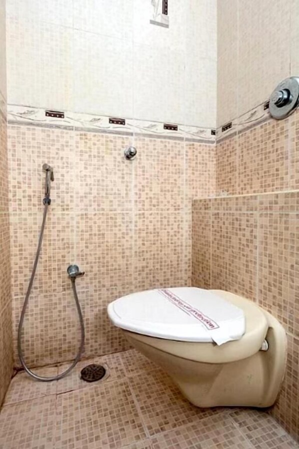 Un baño pequeño con inodoro, ducha y paredes de cerámica.