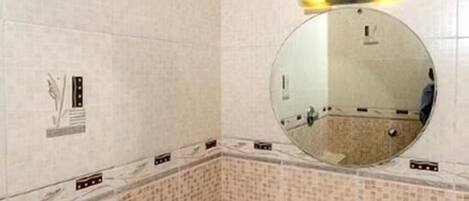 A bathroom with a sink, mirror, and shower.