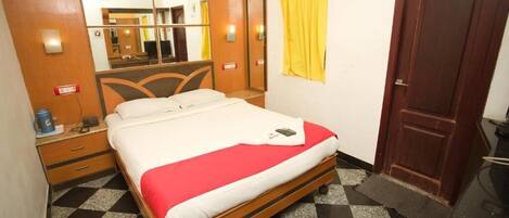 Une chambre d’hôtel avec un lit, un miroir, une armoire, une porte et un comptoir d’enregistrement.