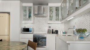 Una cocina moderna con armarios blancos, microondas, estufa y lavabo.