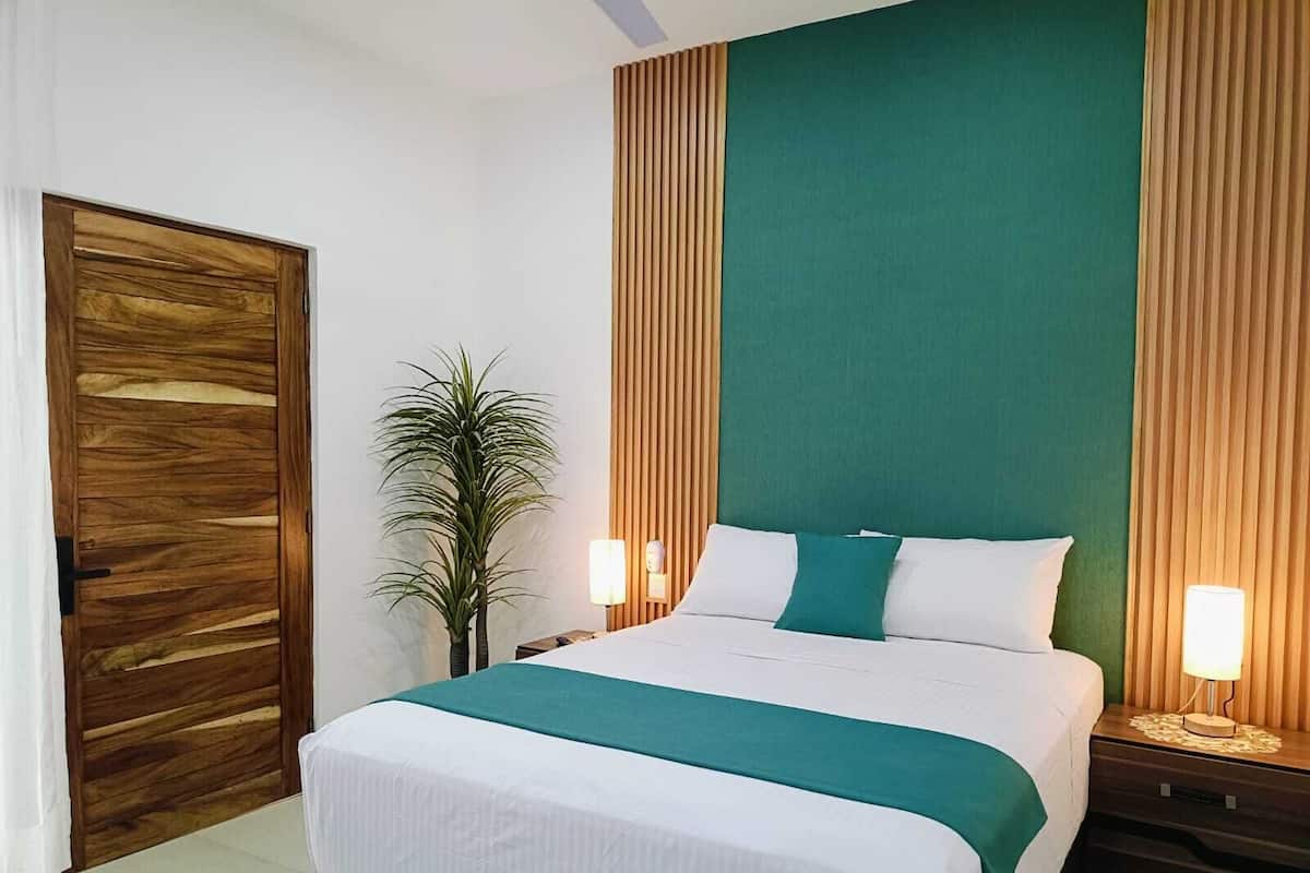 A neatly arranged bedroom with a large bed, wooden headboard, and two bedside lamps.