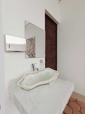 A bathroom with a marble sink, a modern mirror, and a shower area. - Punta Colibrí (Brisas de Zicatela)