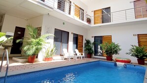 A multi-level hotel with a swimming pool, potted plants, and outdoor seating. - Punta Colibrí (Brisas de Zicatela)