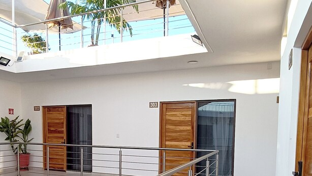 A modern interior with a staircase, a balcony with umbrellas, and a potted plant. - Punta Colibrí (Brisas de Zicatela)