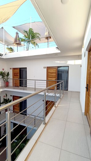 A modern interior with a staircase, a balcony with umbrellas, and a potted plant. - Punta Colibrí (Brisas de Zicatela)