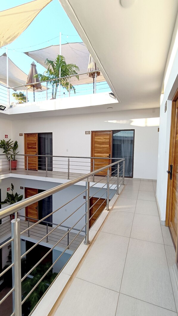 A modern interior with a staircase, a balcony with umbrellas, and a potted plant. - Punta Colibrí (Brisas de Zicatela)