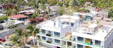 A multi-story building with balconies, a swimming pool, and a view of the ocean.