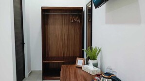 A room with a wooden desk, a television mounted on the wall, a wardrobe, and a small plant. - Punta Colibrí (Brisas de Zicatela)