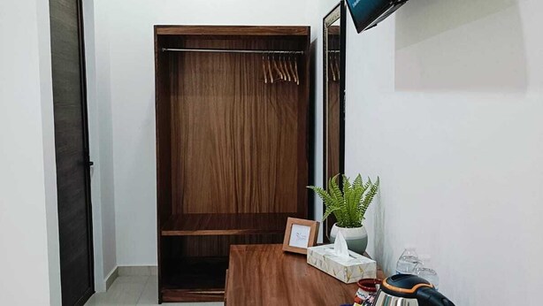 A room with a wooden desk, a television mounted on the wall, a wardrobe, and a small plant. - Punta Colibrí (Brisas de Zicatela)