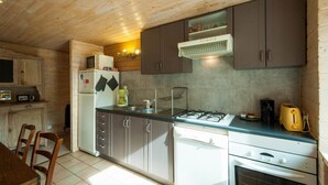 Une cuisine compacte avec des meubles en bois, une cuisinière à gaz, un four à micro-ondes et un évier.