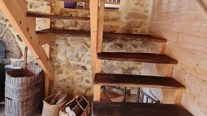 Un escalier en bois, avec des murs en pierre et un sol carrelé.