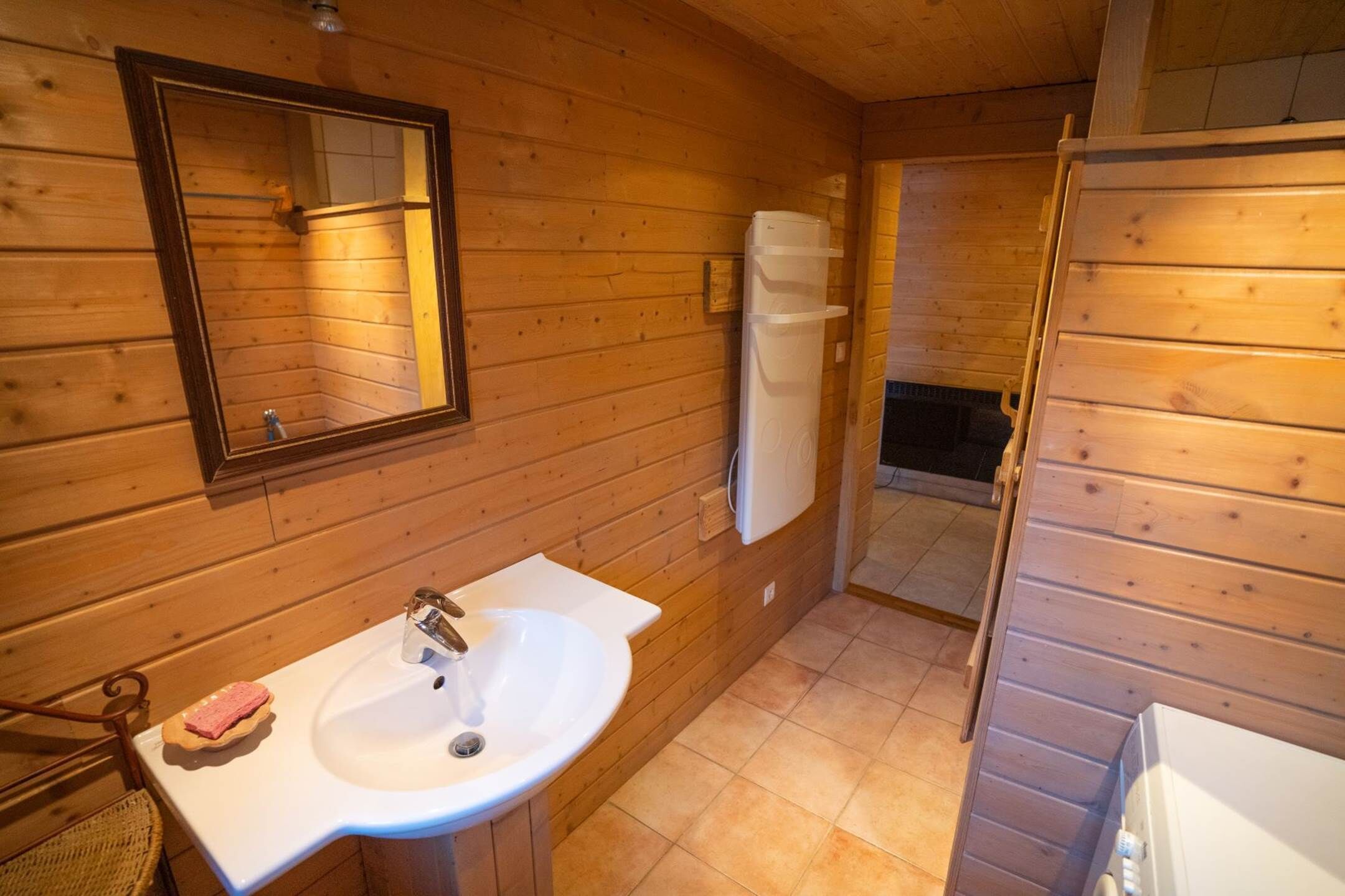 A wooden cabin bathroom with a sink, mirror, and a white towel rack.