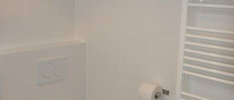 A small, white bathroom with a toilet, a towel rack, and a toilet paper holder.