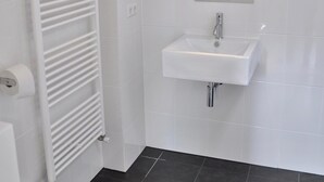 Een badkamer met een witte radiator, een wastafel en een spiegel.