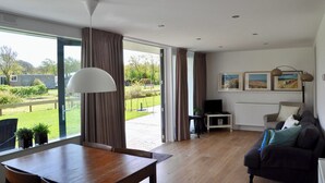 Een ruime woonkamer met een groot raam, een eettafel, een bank en een televisie.