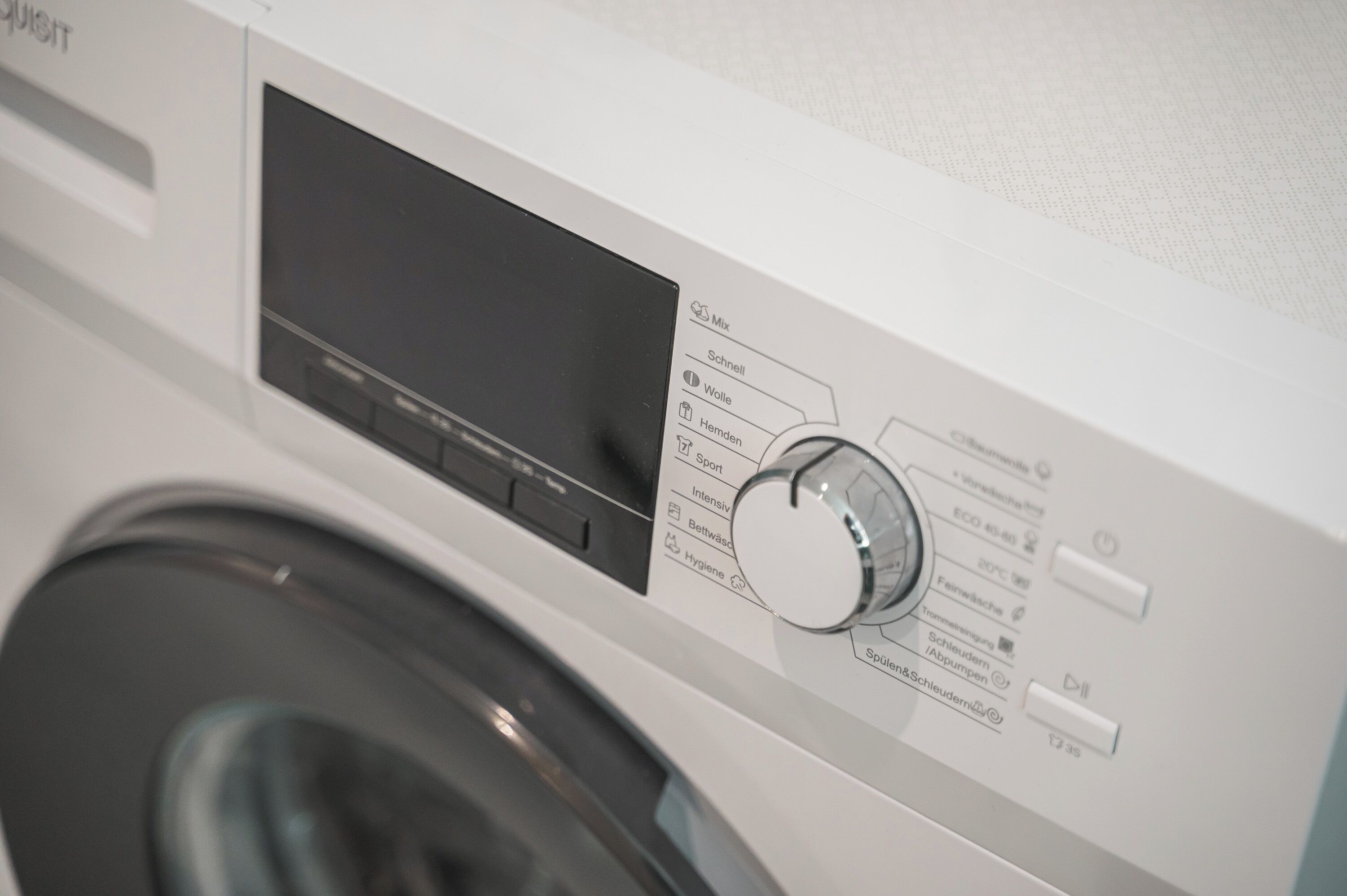 Een voorzichtszicht van een wasmachine met bedieningspaneel, inclusief een digitaal scherm en diverse knoppen voor instellingen.