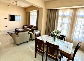 Una sala de estar moderna con sofá, sillas, una mesa de comedor y televisor.