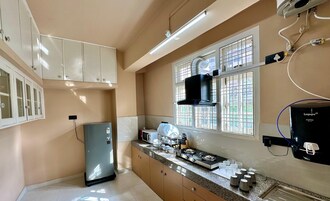 Cocina con refrigerador, estufa y ventana con rejas.