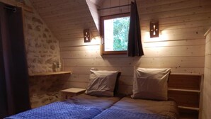 A cozy bedroom with a wooden ceiling, a window with curtains, a bed with pillows, and a nightstand. - Nature-themed Bed and Breakfast (Broye)