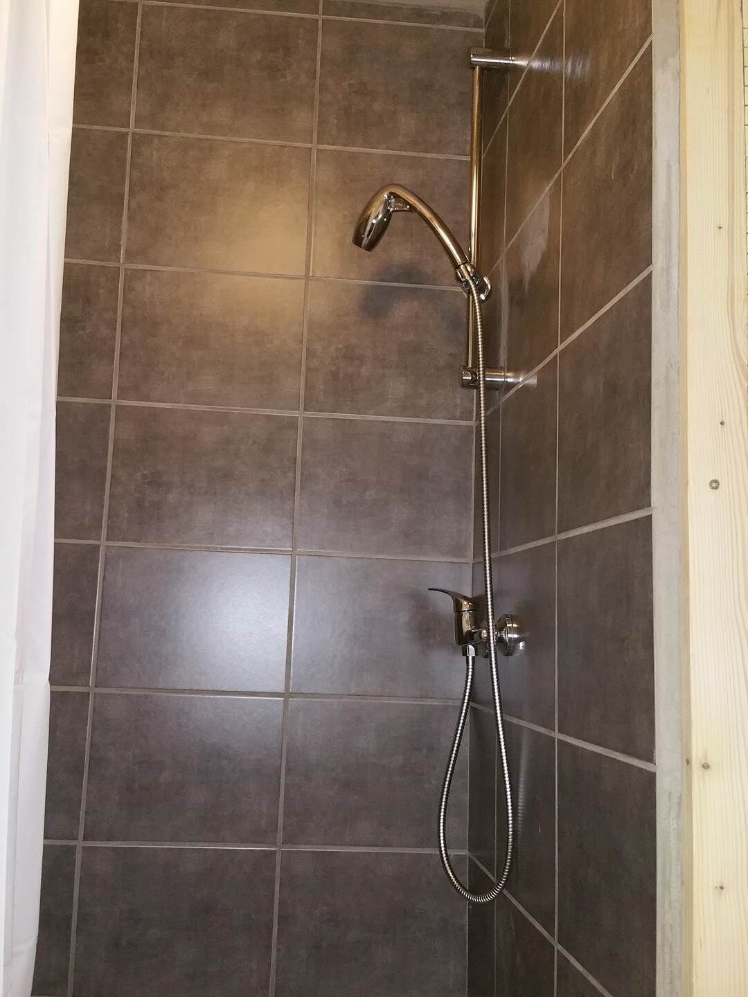 A shower with a handheld showerhead and a fixed wall-mounted showerhead.