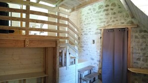 A rustic room with a wooden staircase, a stone wall, and a wooden bench. - Nature-themed Bed and Breakfast (Broye)