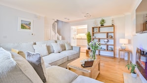 Ein geräumiges Wohnzimmer mit einem grauen Sofa, einem Holztisch und einem Bücherregal.